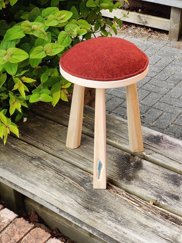Three legged stool with red dyed upholstery on top (round)