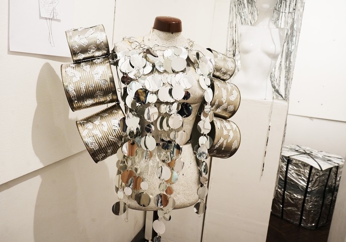 A top made of tin cans and reflective silver material on a mannequin