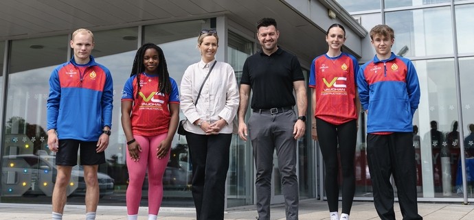 Sponsors Adam Thomas from Vaughan Construction standing outside Graig campus with sports students