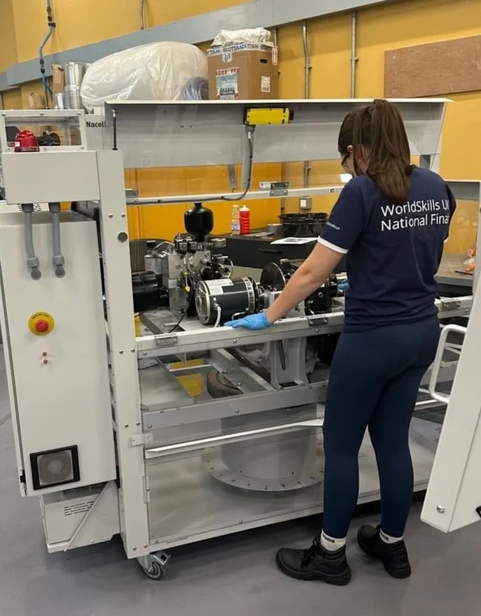Emily working at a skills competition with some equipment wearing a branded skills top