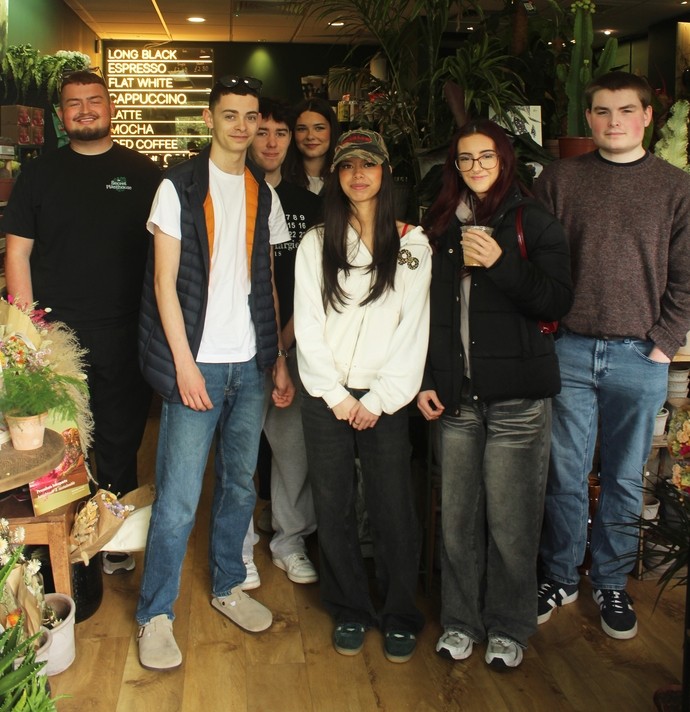 Students in the Secret PlantHouse shop standing in a line with Cameron the owner in a dimly lit calm environment