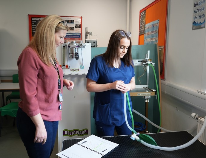 A student being shown a piece of apparatus by her lecturer it appears to be a long tube
