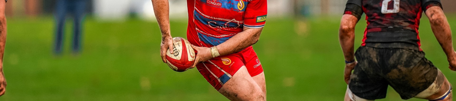 Student in red sports kit about to pass a rugby ball.