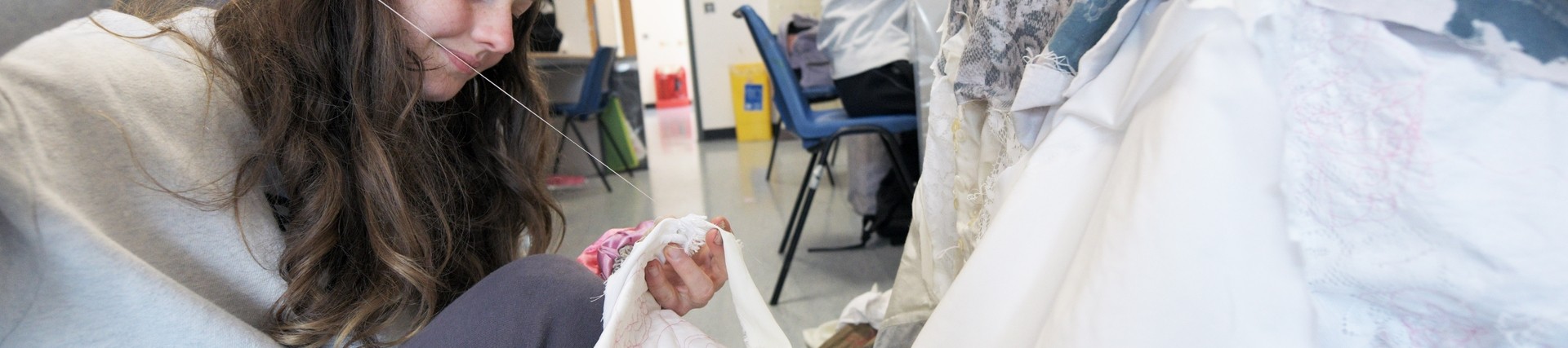 A student stitches a dress.