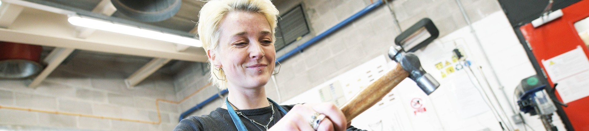 A student hammers some jewellery into shape.