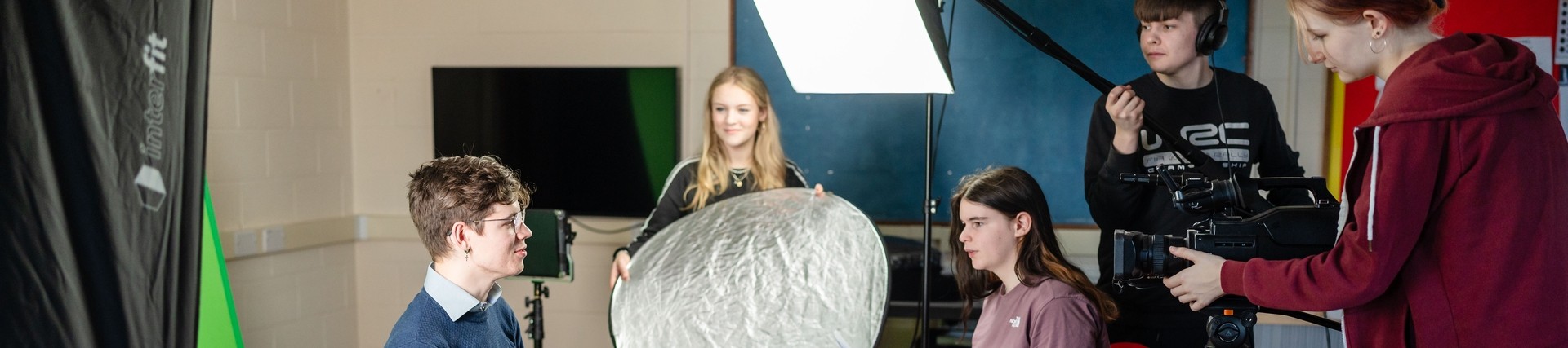 Group of students filming interview using equipment