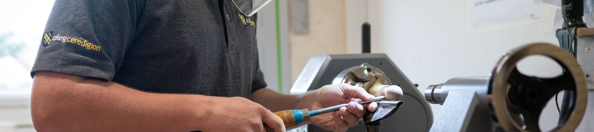 Student working on piece of furniture at machine