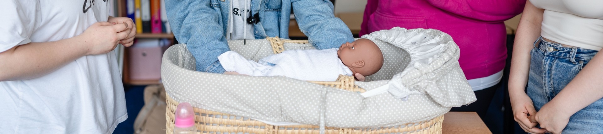 students and tutor with dummy baby in crib