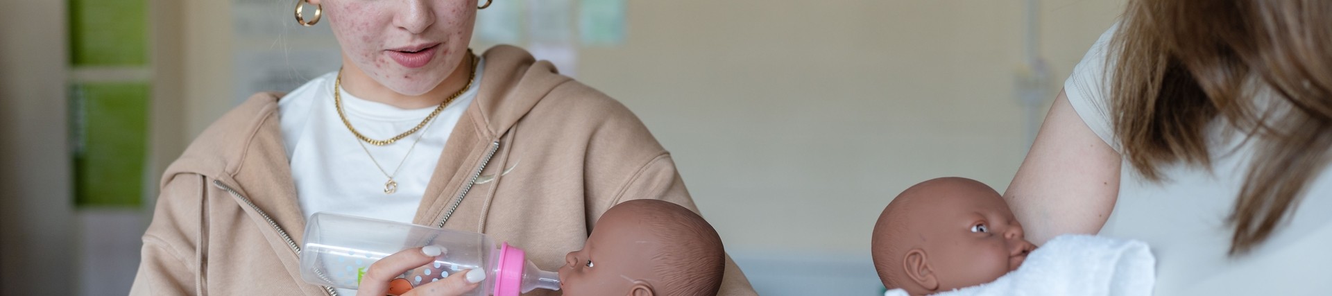 Student cradling dummy baby with baby bottle