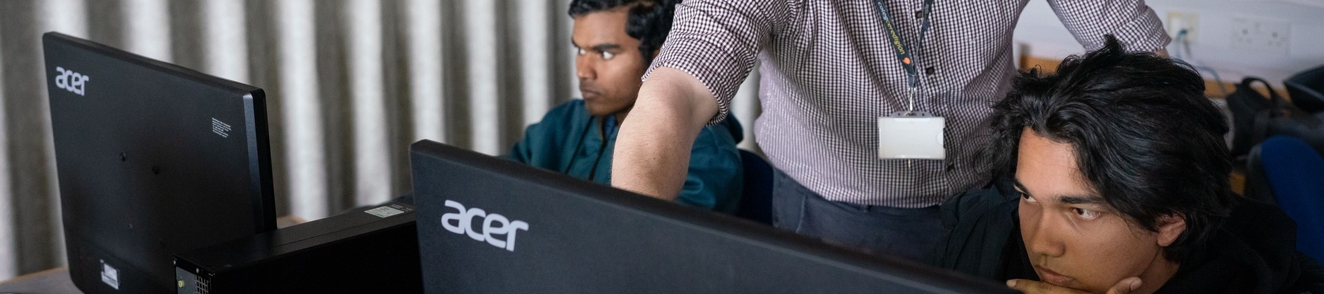 Tutor helping student sat at computer