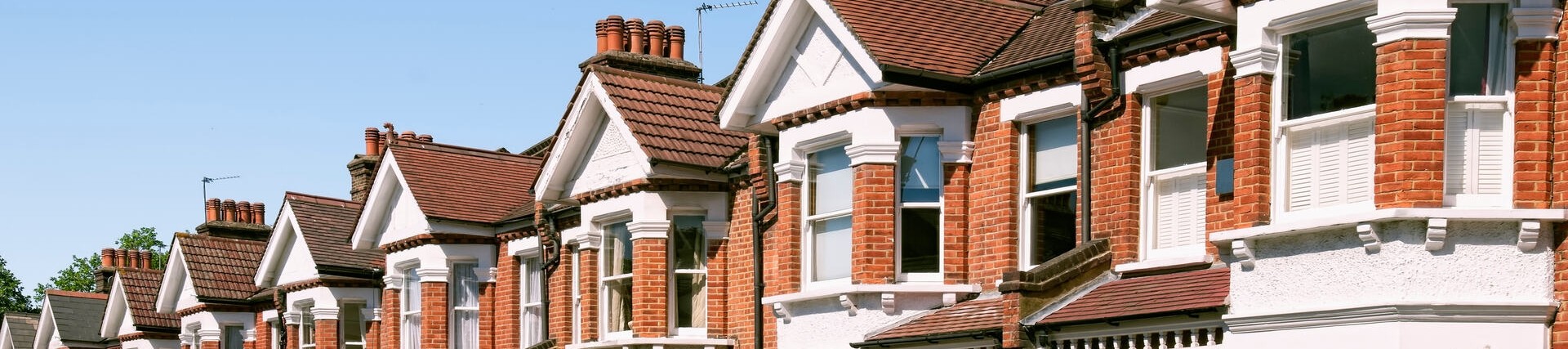 A row of orange-bricked houses on a nice day with a clear blue sky