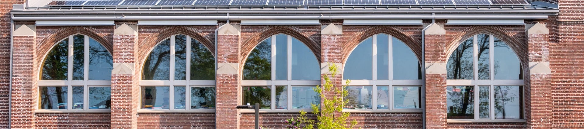 Orange-bricked building with solar panels on the roof, nice day, blue skies
