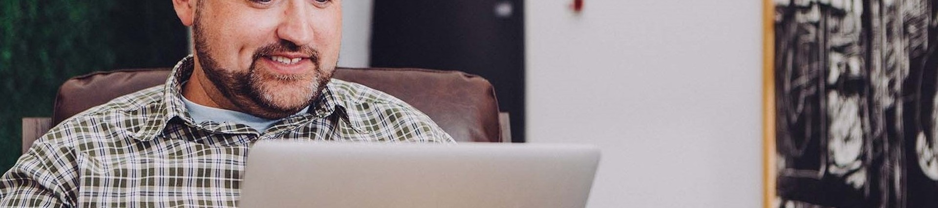 A male sitting while using an Apple laptop