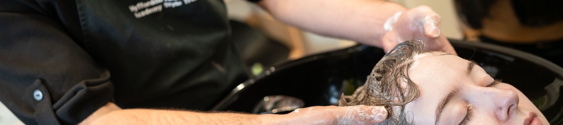 student at basin washing clients hair