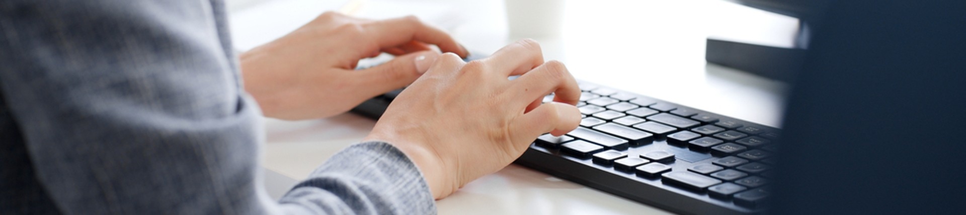 Hands of unseen person working a computer