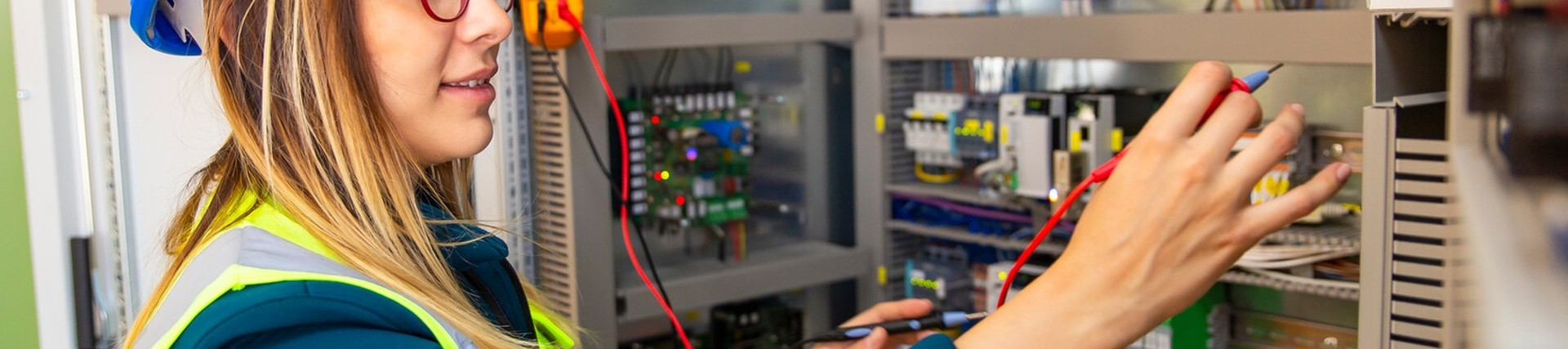 Female electrician wearing a hi vis and hard hat, working on a fuse box