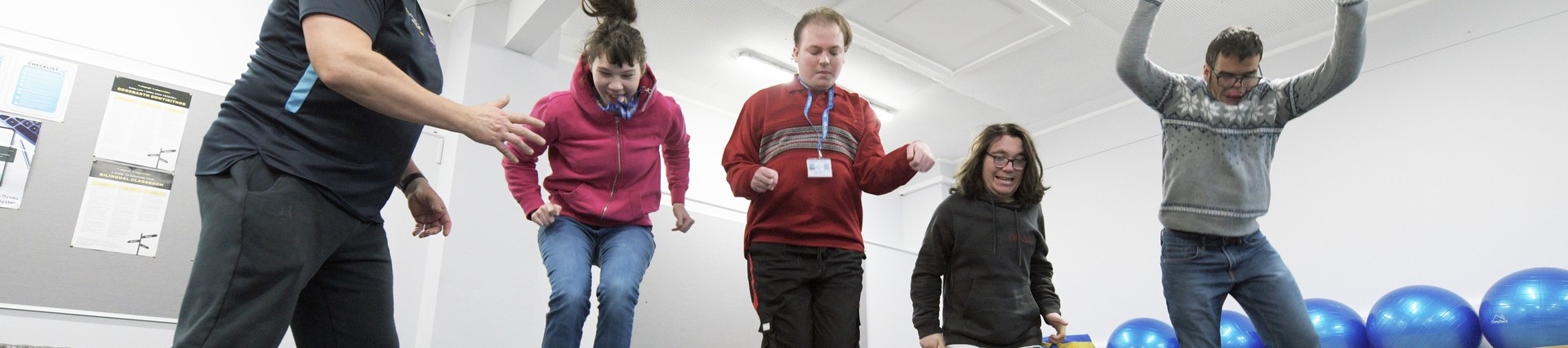 Independent learning students jumping over equipment in sport lesson 