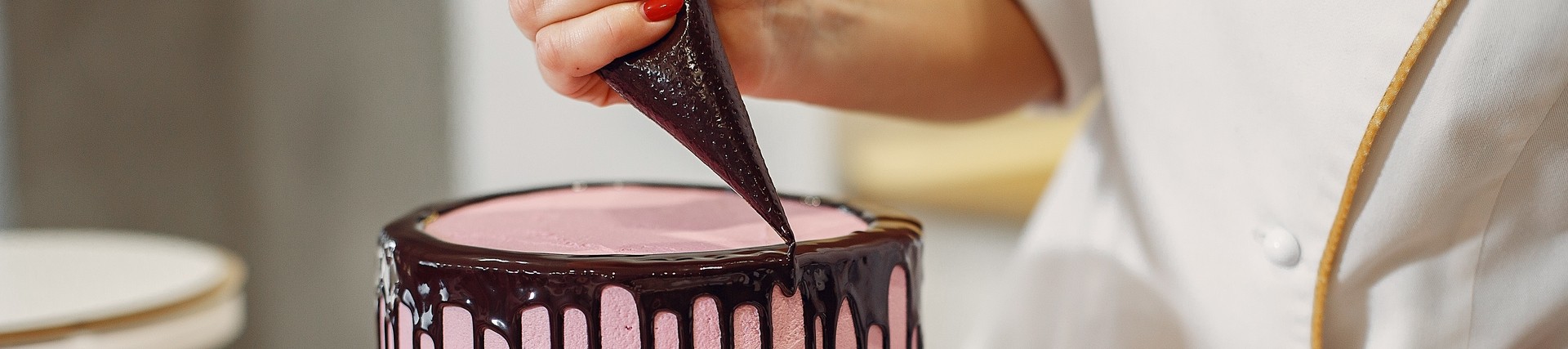 pink cake being decorated with dark chocolate icing drips