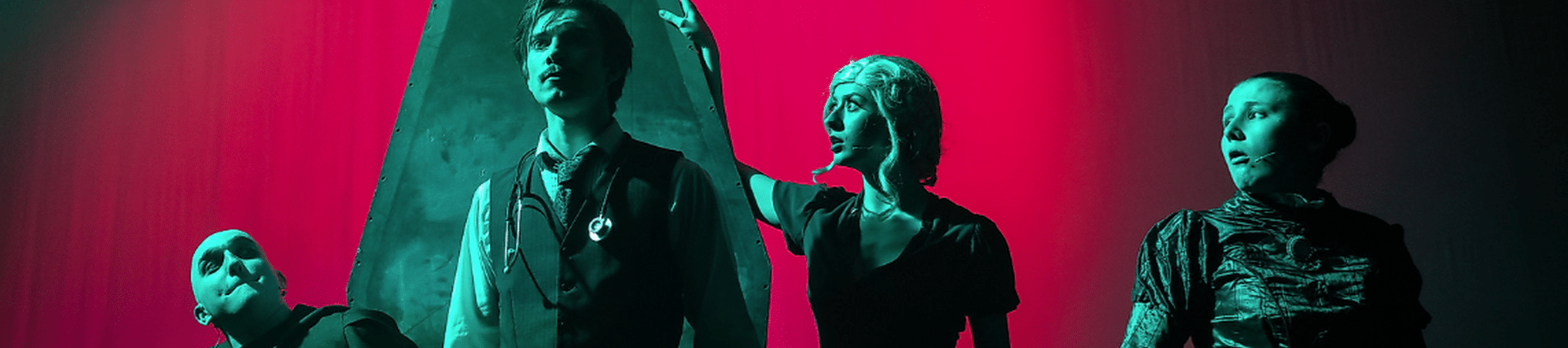Stark contrast red background and 4 figures almost silhouetted in foreground stood by a coffin. From performance of Young Frankenstein.
