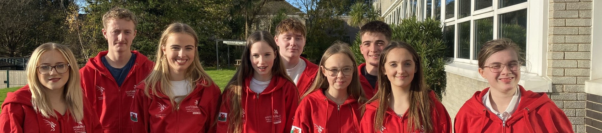 A group of students in red competition hoodies standing together, smiling
