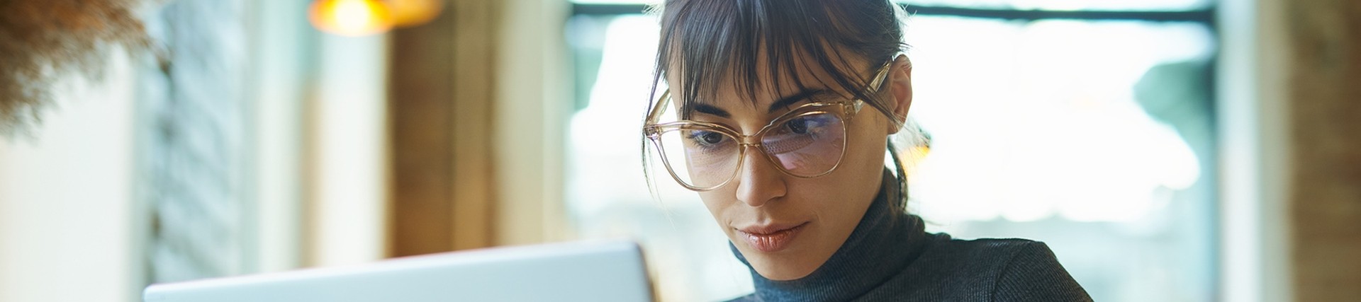 Brunette female with glasses working at a laptop