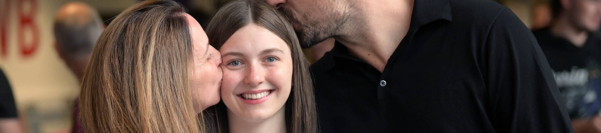 Lily with her mum and dad kissing her head