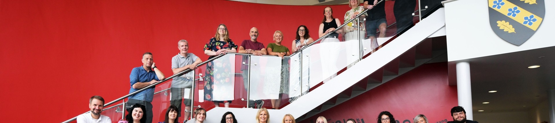 All the A-level tutors lined up on the stairs and balcony with the lighted up words Da Iawn at the bottom 