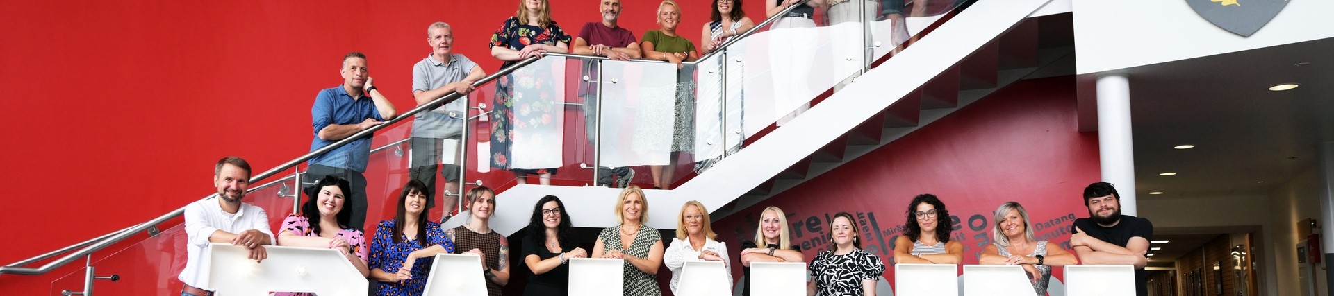 All the A-level tutors lined up on the stairs and balcony with the lighted up words Da Iawn at the bottom 