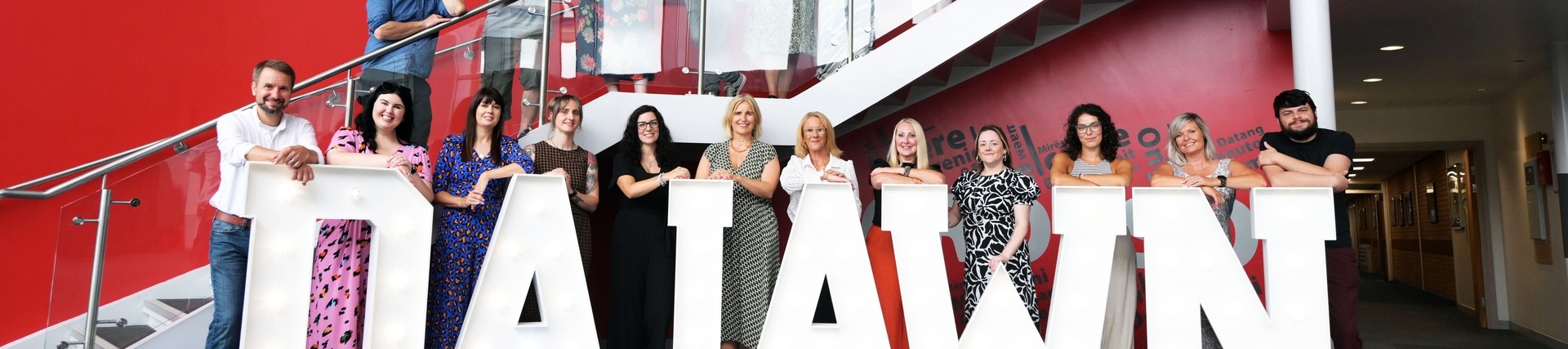 All the A-level tutors lined up on the stairs and balcony with the lighted up words Da Iawn at the bottom 
