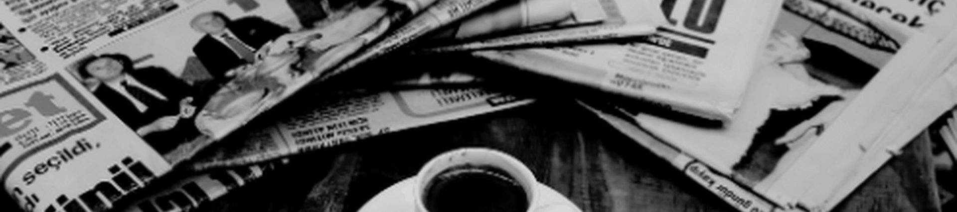 Black and white newspapers with a cup of coffee in the middle