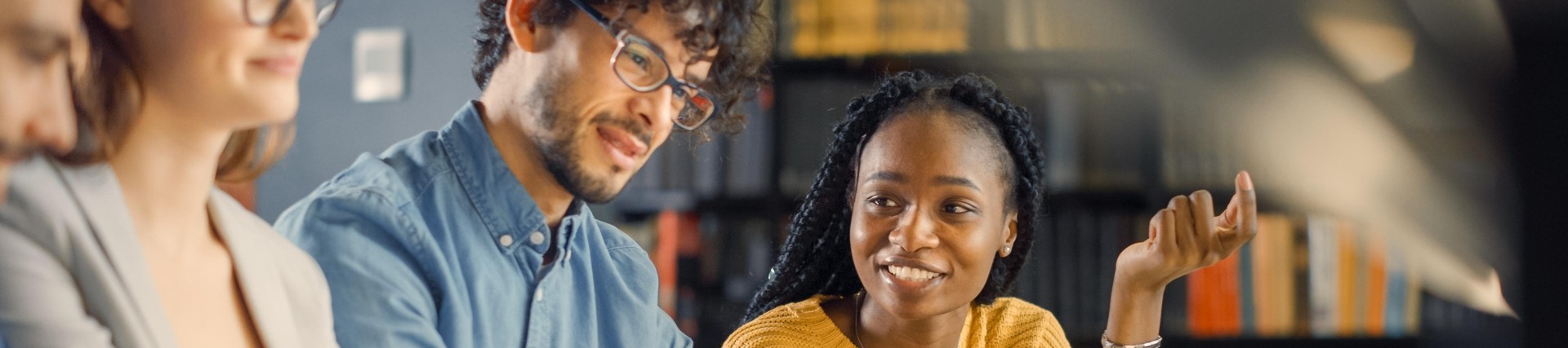 a groupf diverse young adults studying in a library setting
