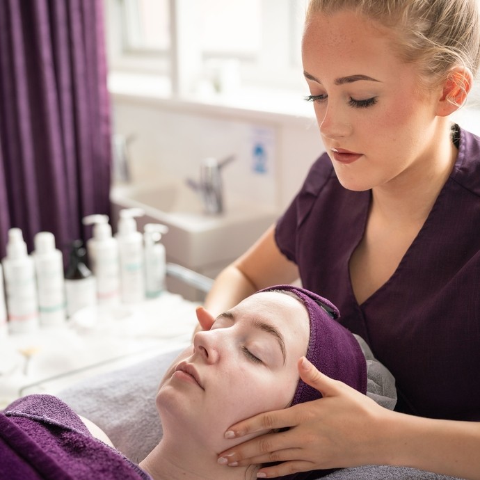 Close up of student in purple uniform giving someone a facial.