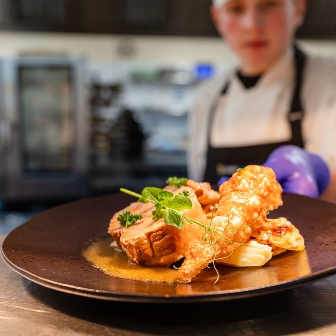 Catering student plating food at the pass.