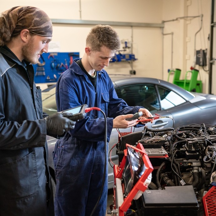 Two automotive students fixing a car.