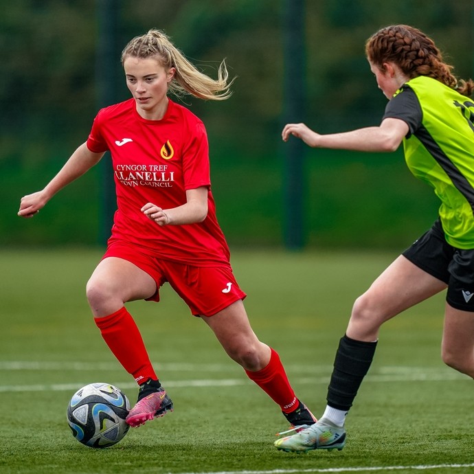 Two female student athletes playing football.