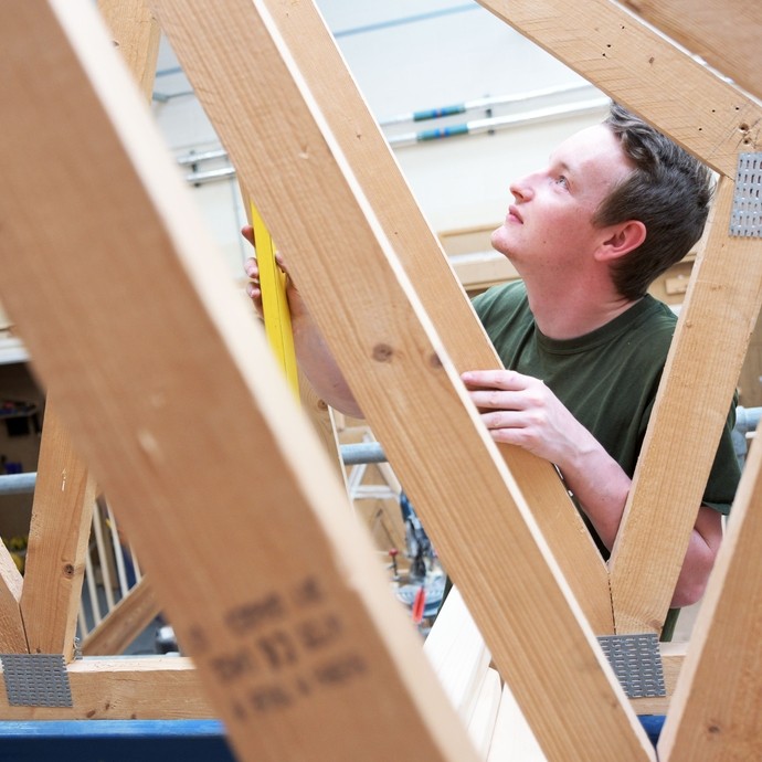 Construction student measuring a timber frame.