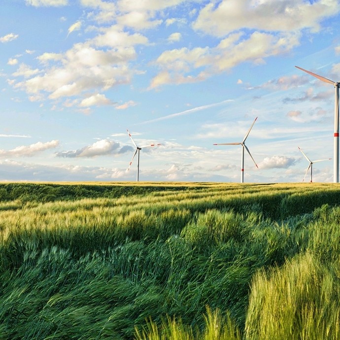 Wind turbines visible in a green field. It's a nice day with clouds in the blue sky