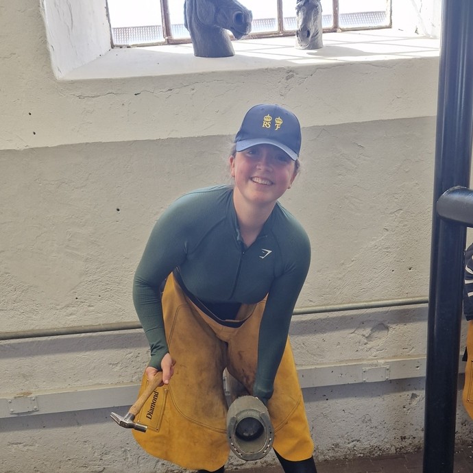 A student using a fake hoof doing shoe work