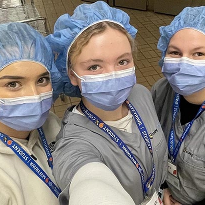 three students in medical masks and hats in a selfie