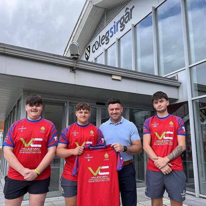 Adam from Vaughan Construction outside the college pictured with some team members wearing red kit and holding up a shirt