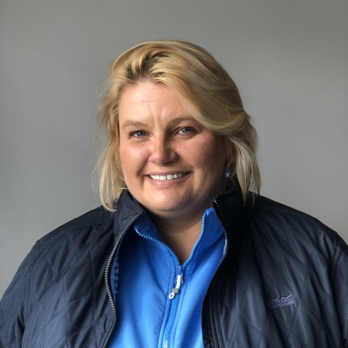 Olga in a blue top and coat in a headshot