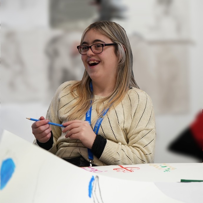 A student working and smiling by a desk