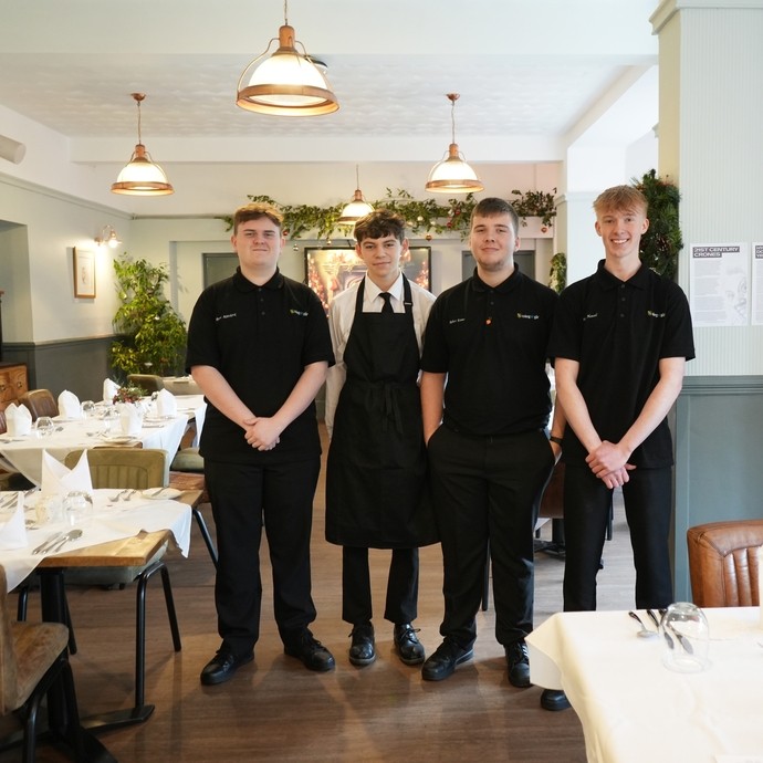 Four catering and hospitality students standing in a training restaurant