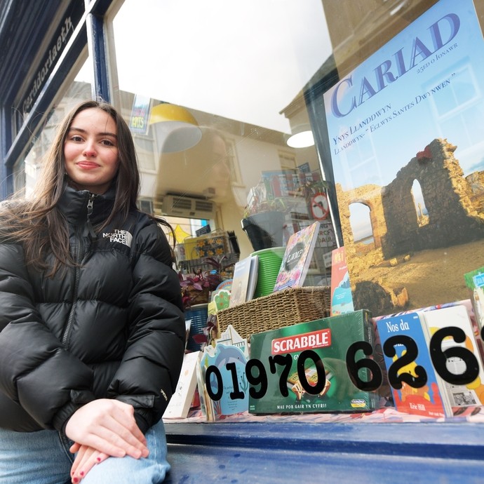 Student outside a shop window in Aberystwyth town 