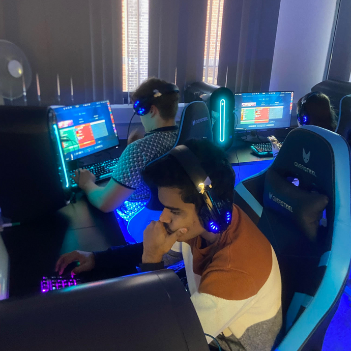 Students in the esports room it's dark with lots of bright colours coming from the screens