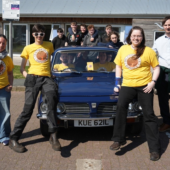 Students surrounding and inside the car with Sister Ally and some are wearing yellow branded Skanda Vale tshirts