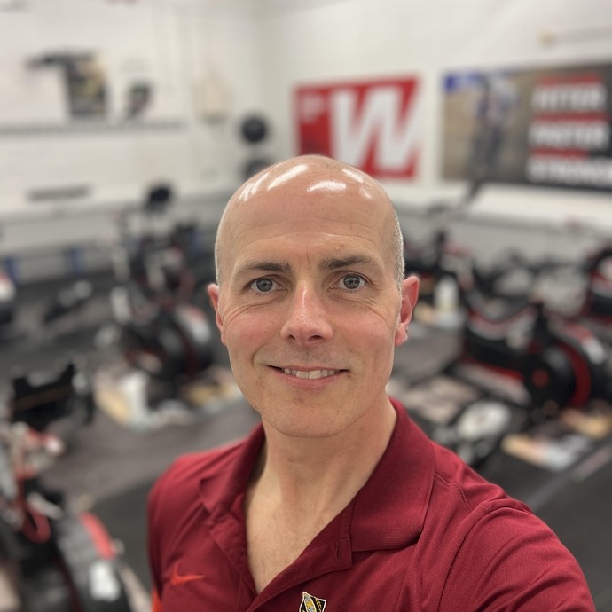 Rob Kirk in a maroon top with a blurred weights background