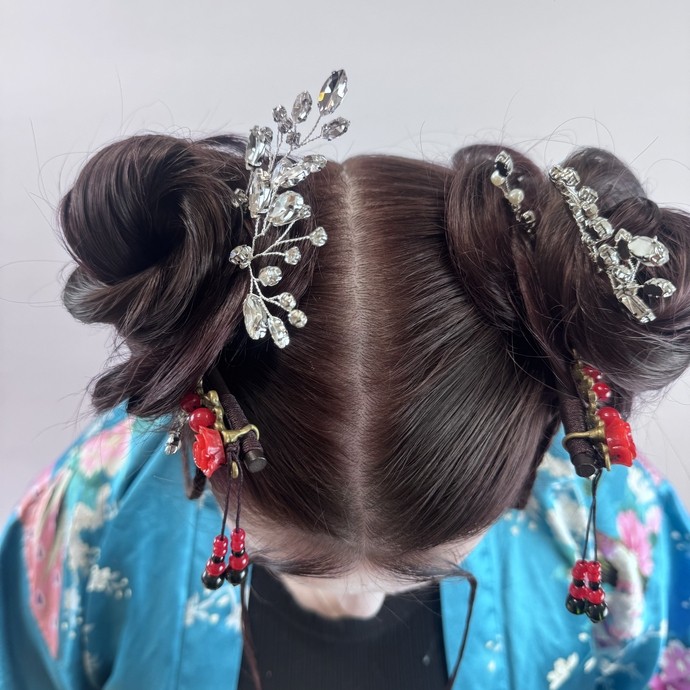 A model with head down, showing a parted/bun hairstyle and accessories
