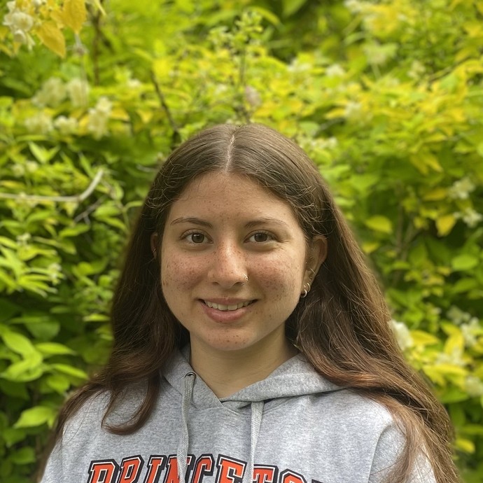 Hannah in front of some greenery wearing a Princeton hoodie
