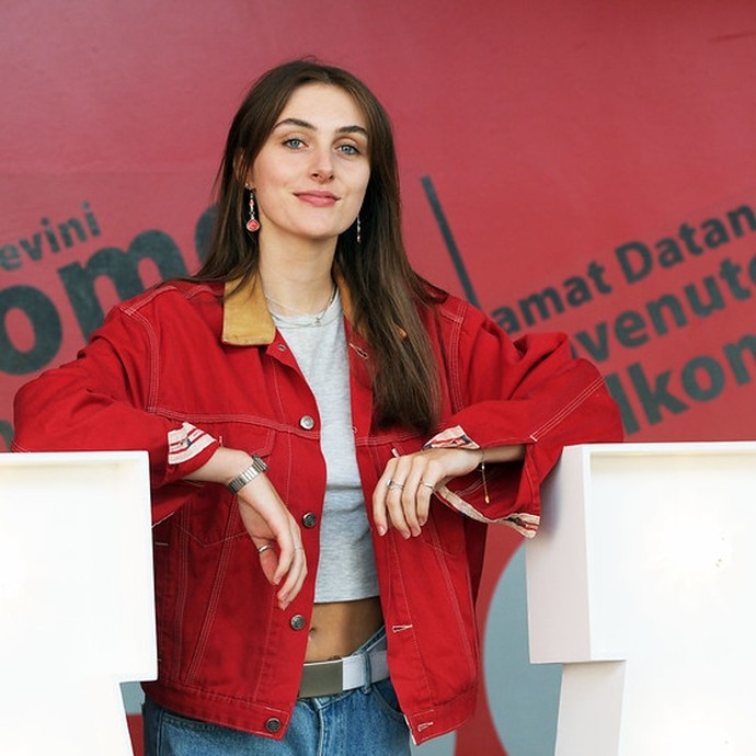 Girl with red jacket standing against a red background
